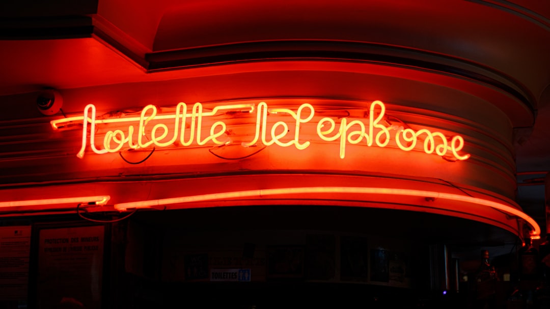 Red telephone booth on a city street at night.