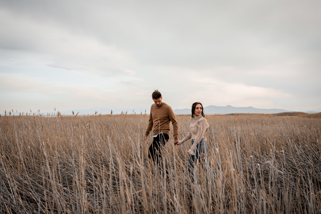A man and a woman standing in a field of tall grass