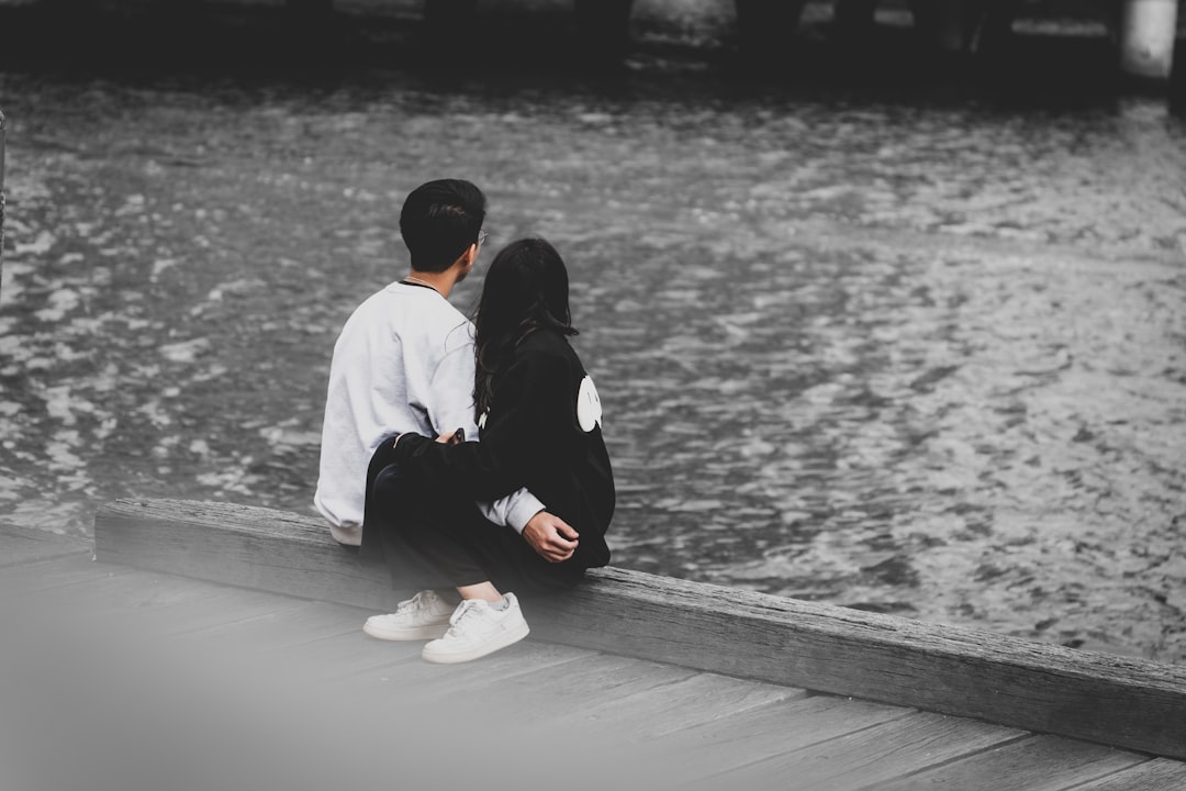 Couple holding broken heart halves on pink background