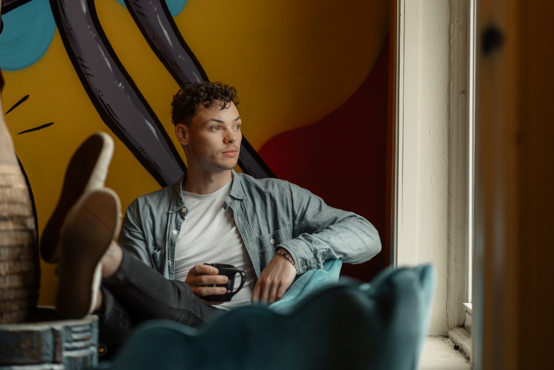 man sitting on cafe while holding smartphone